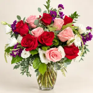Blushing Hues flower arrangement with red and blush roses, white blooms, purple flowers, and greenery in a clear glass vase by a Santa Monica florist