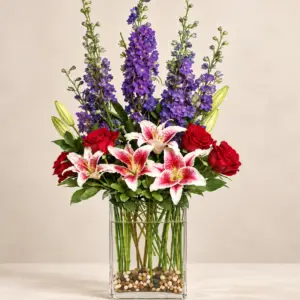 Garden Sonata arrangement with violet delphinium, Stargazer lilies, red roses, and greenery in a clear rectangular glass vase by a Santa Monica florist