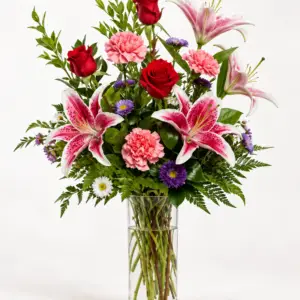 Harvest Meadow mixed flower arrangement with red roses, pink lilies, carnations, purple flowers, and greenery in a clear glass vase by a Santa Monica florist