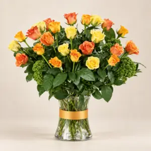 Rosy Radiance arrangement with apricot, orange, and yellow roses, green accent flowers, and fresh foliage in a clear glass vase by a Santa Monica florist