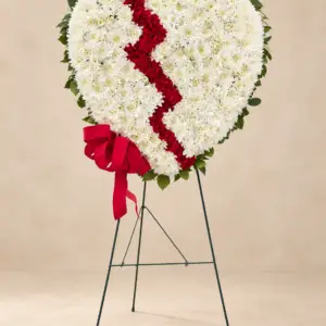 Broken Heart standing funeral tribute with white chrysanthemums, a red floral center, red ribbon bow, and greenery by a Santa Monica florist