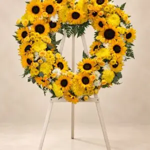 Golden Remembrance sunflower funeral heart wreath with yellow roses and chrysanthemums on a standing easel by a Santa Monica florist